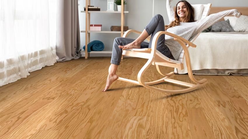 A person sitting on a rocking chair in a bright room with engineered timber flooring, showcasing the smooth finish and modern aesthetic of this flooring type.